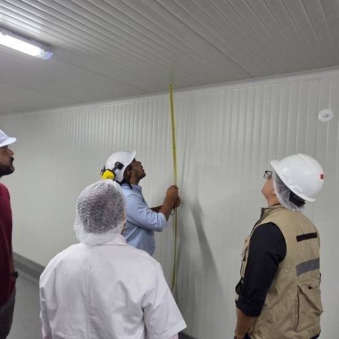 Verificación de medidas en un cuarto frío durante la entrega de obra