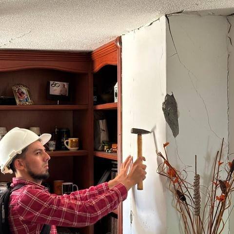 Ingeniero con casco descubriendo el pañete de una columna fisurada para evaluar daños por sismo