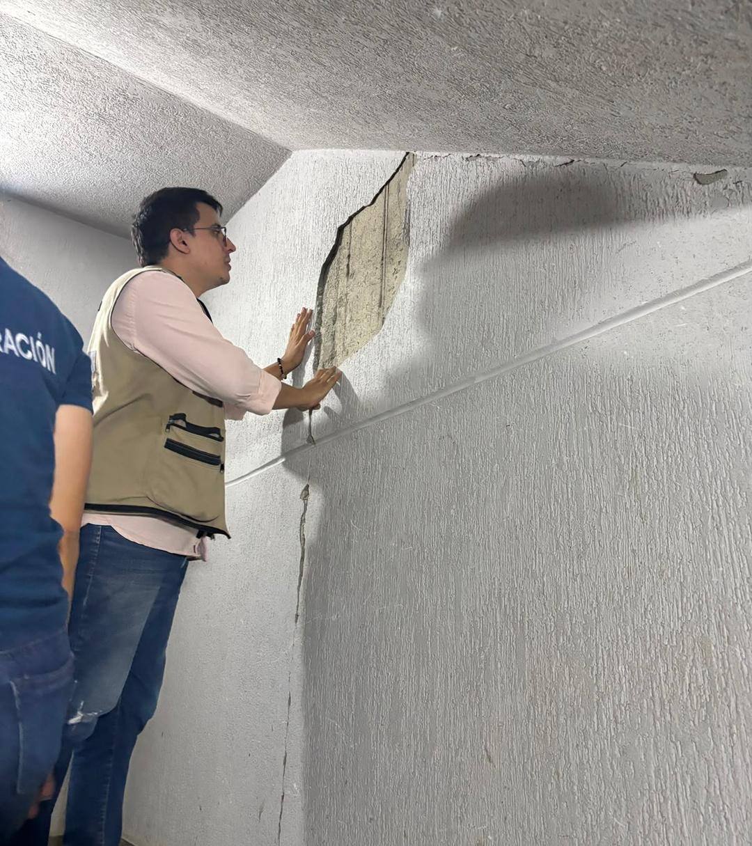 Ingeniero estructural revisando una grieta en el muro de una escalera durante una visita técnica