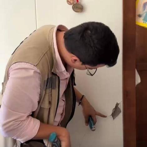 Ingeniero señalando una fisura en el muro de un apartamento durante la inspección