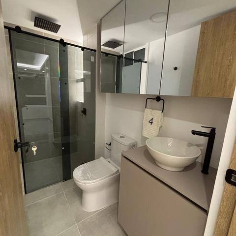 Baño remodelado con división en vidrio y mueble de lavamanos
