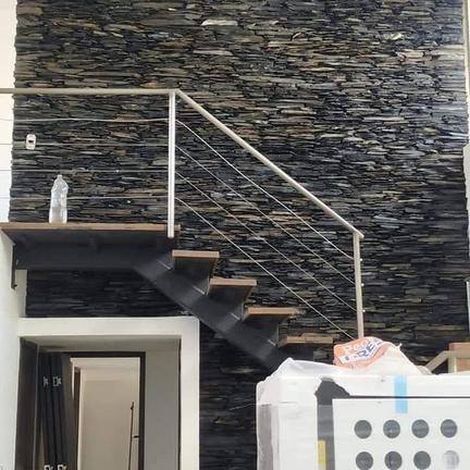 Escalera con huellas metálicas y muro en piedra laja